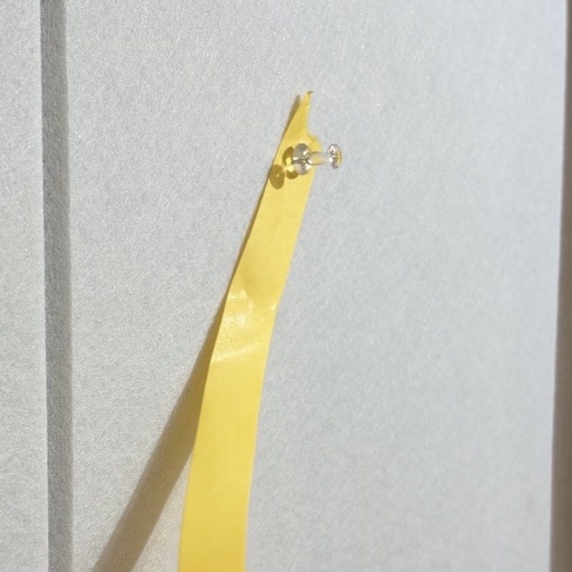 紙テープの端を壁面に留める様子